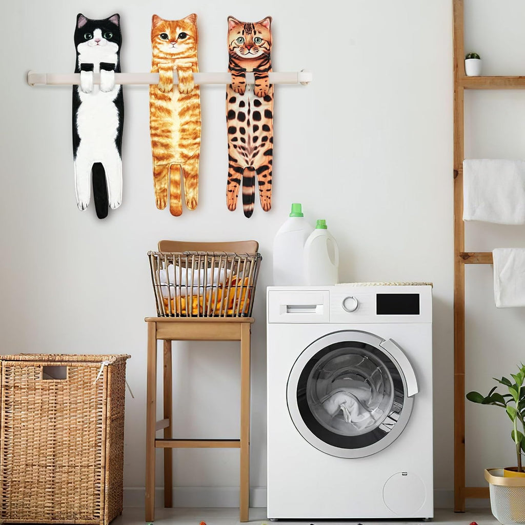 Three cat towels hanging on a wooden rail in a laundry room